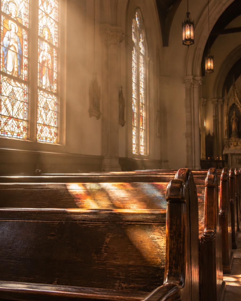 Morning light through stained glass onto wooden pews